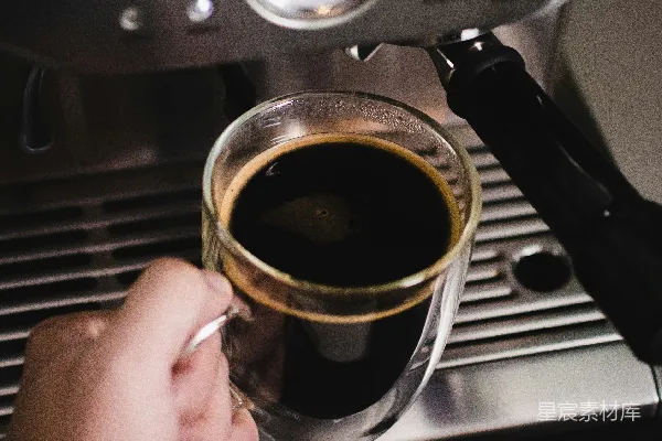 手持透明玻璃杯的人举着一杯棕色液体