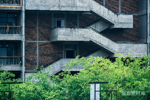 高清摄影 砖砌建筑上的混凝土楼梯，周围绿意盎然。
