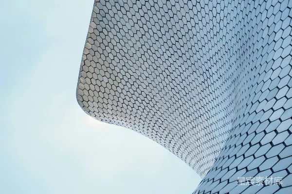 高清摄影 现代化的建筑物，其六边形的外墙在浅蓝色的天空下弯曲。