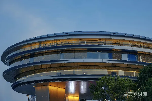 高清摄影 现代的圆形建筑在晴朗的天空下，内部灯光璀璨。