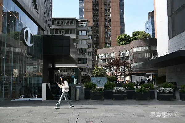 高清摄影 一个女人在阳光明媚的日子里走过现代化的建筑。
