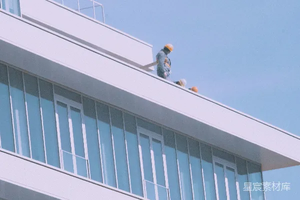 高清摄影 在一座现代化的白色建筑顶端的工人。