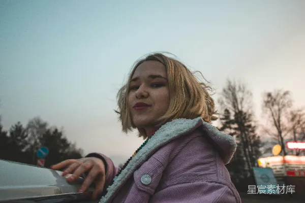 身穿紫色夹克的女人在白天手持着银色的智能手机