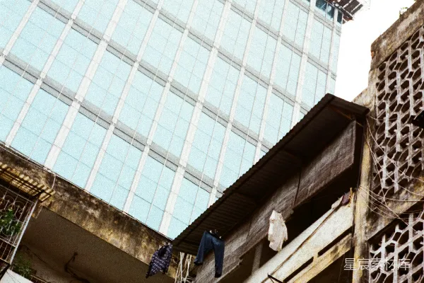 高清摄影 现代化的玻璃建筑俯瞰着旧公寓，晾衣绳上挂着衣物。