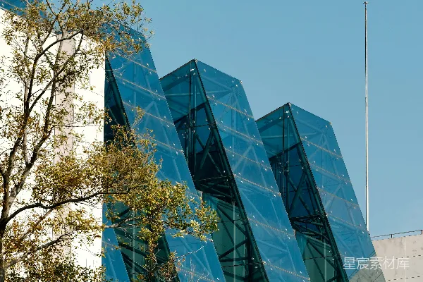 高清摄影 现代玻璃建筑前有树木，背景是蓝天。