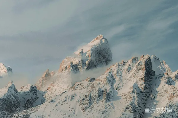 山峦被雪覆盖，在一片阴云的天空下