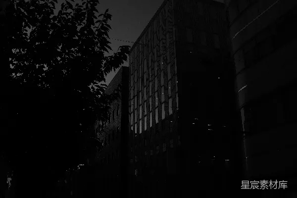 高清摄影 黄昏时分，一栋黑暗的建筑外墙映衬着被灯光照亮的窗户。