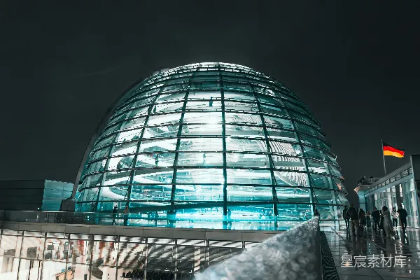 高清摄影 夜晚的现代玻璃穹顶建筑，背景中有德国国旗。