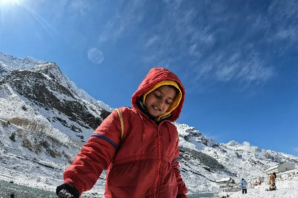 一个穿着红色滑雪服的小孩站在雪地里。