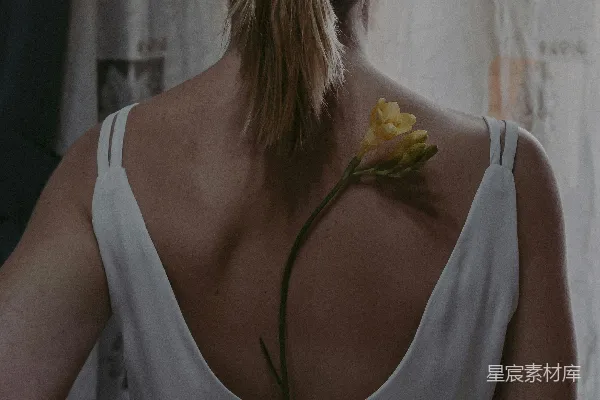 白色上衣的女人，头上戴着黄色的花朵。