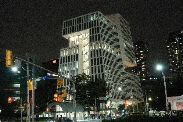 高清摄影 现代的照明建筑物在夜晚，旁边有交通信号灯。