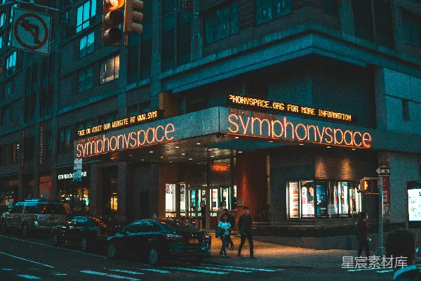 高清摄影 在夜间，人们在交响乐空间商店旁边散步。