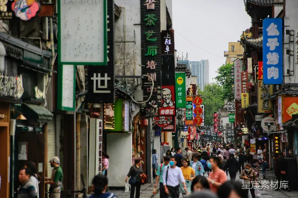 高清摄影 一群人在高楼旁边沿着街道行走。
