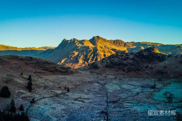 蓝天白云间翠绿与褐黄山色的昼景