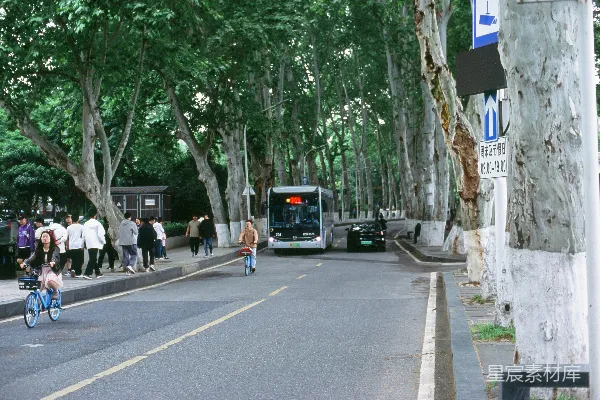 高清摄影 一群人沿着街道走过，旁边有一辆公交车。
