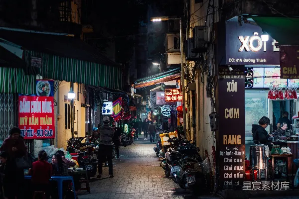 高清摄影 夜晚的一条狭窄街道，人们坐在桌旁。