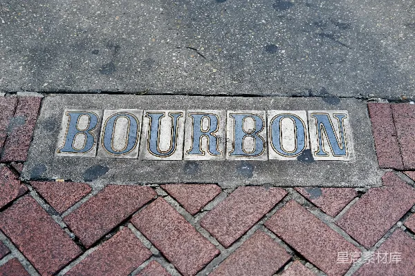 高清摄影 一个写着“bourbon”的标志牌放在人行道上。