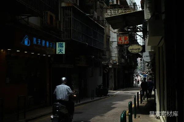 高清摄影 一个男人骑着摩托车沿着街道行驶，旁边是高楼大厦。
