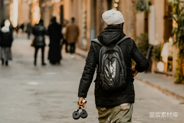 高清摄影 一个男人背着背包走在街上。