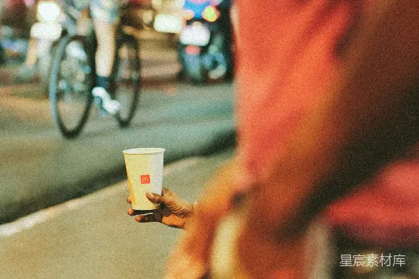 高清摄影 一个手里拿着一杯咖啡的人站在街角。