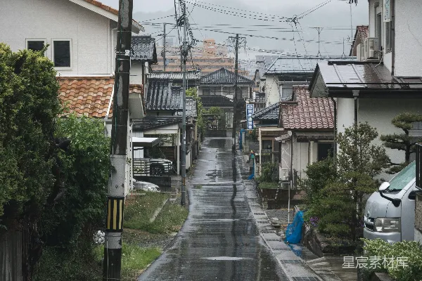 高清摄影 一条湿漉漉的街道，两旁是房屋和电线。