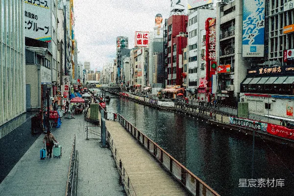高清摄影 城市运河旁，建筑物林立，人们沿着水边散步。