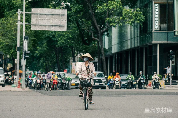 高清摄影 一个男人骑着自行车沿着街道行驶，旁边是高楼大厦。