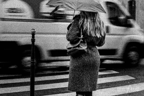 高清摄影 一个女人打着伞走过街道。