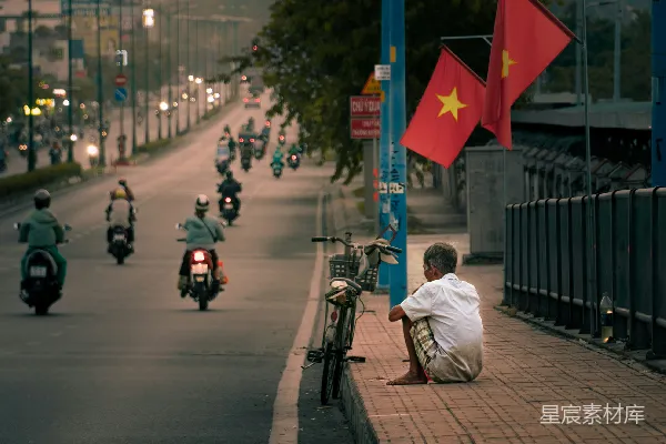 高清摄影 一个男人坐在路边，旁边有一辆摩托车。