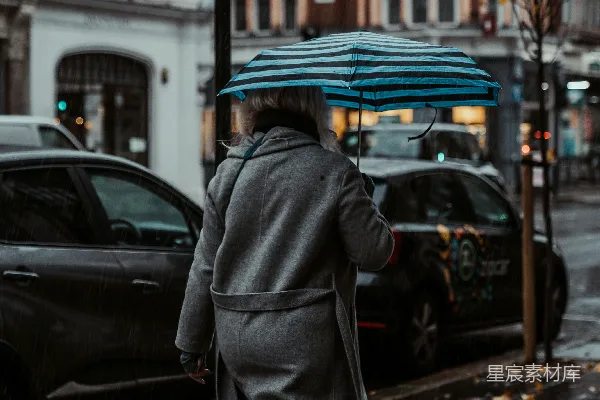 高清摄影 一个穿着灰色外套的女人站在人行道上。