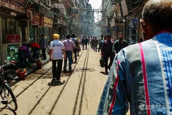 高清摄影 一个男人正在高楼大厦旁骑自行车沿着街道行驶。