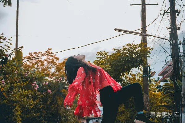 高清摄影 穿着红色衬衫和黑色裤子的女人白天在街上跳跃。