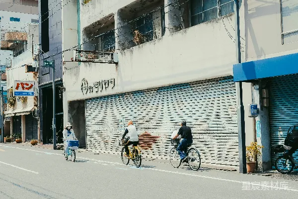 高清摄影 在街道上骑车的人，旁边是关闭的商店。