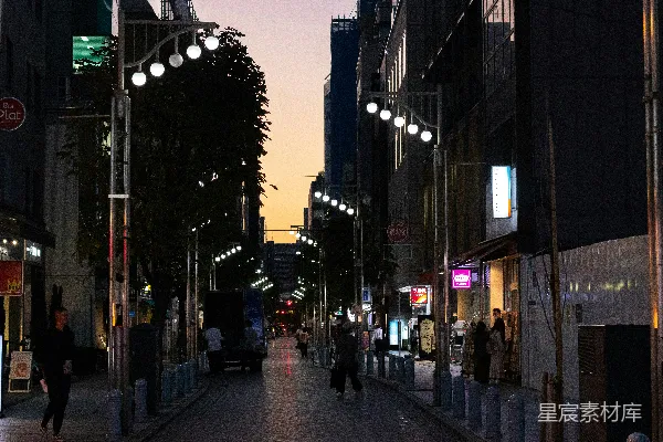 高清摄影 一个夜晚的城市街道，人们在人行道上行走。