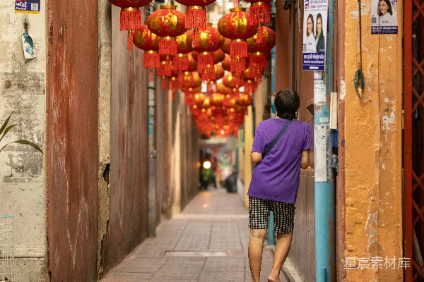 高清摄影 一个女人在红灯笼下沿着街道行走。