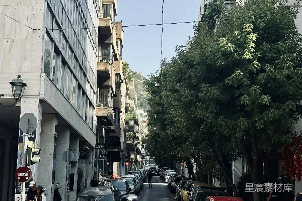 高清摄影 一个男人骑着摩托车沿着街道行驶，旁边是高楼大厦。
