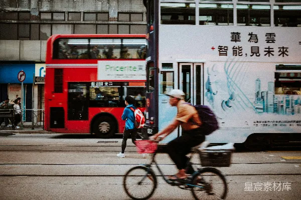 高清摄影 一个男人骑自行车沿着街道经过一辆公交车。