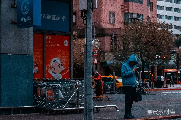 高清摄影 穿蓝色连帽衫的男人在城市街道上查看手机。