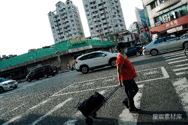 高清摄影 带着行李箱的女人横穿繁忙的城市街道