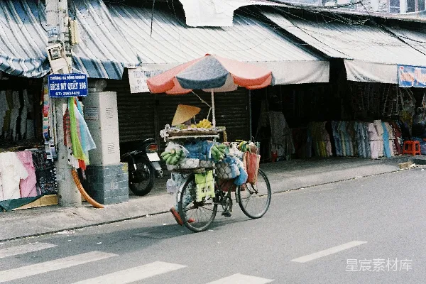 高清摄影 一个男人在高楼旁边沿着街道骑自行车。