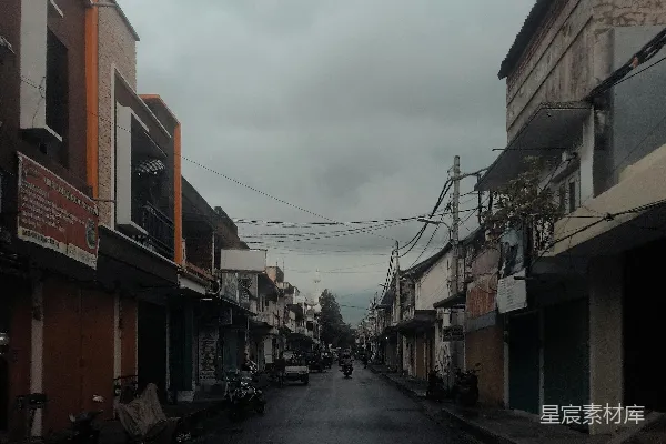 高清摄影 一条黑暗的街道，街道两旁是建筑物，一辆摩托车停在街道一侧。
