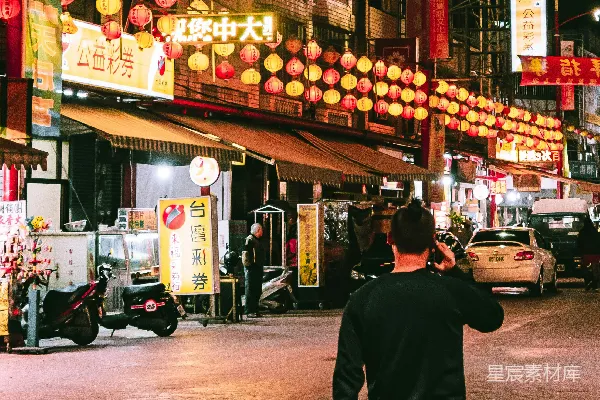 高清摄影 穿着黑色衬衫和红色裤子的男人站在商店附近，夜幕降临。