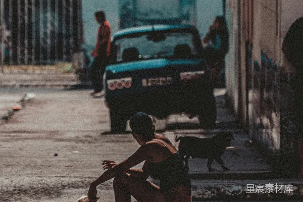 高清摄影 穿着黑色背心的男人坐在人行道上，白天。