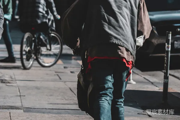 高清摄影 穿着黑色夹克和蓝色牛仔裤的男人在白天的人行道上行走。