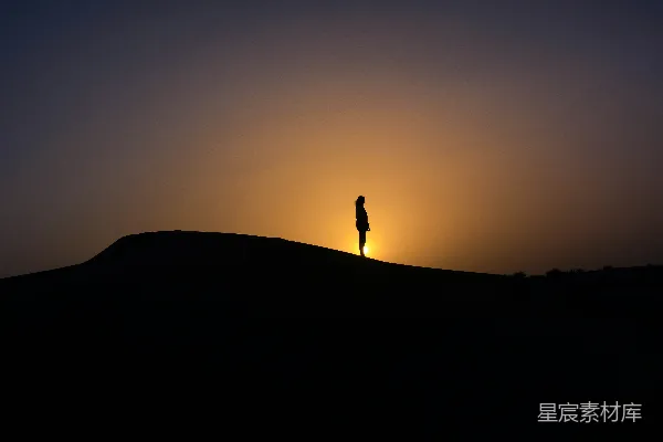 山头站立人的 silhouette 在夕阳西下时的景象