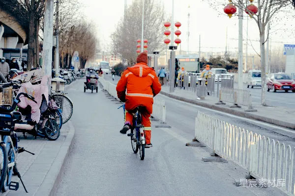 高清摄影 一个穿着橙色夹克的男人骑着自行车沿着街道行驶