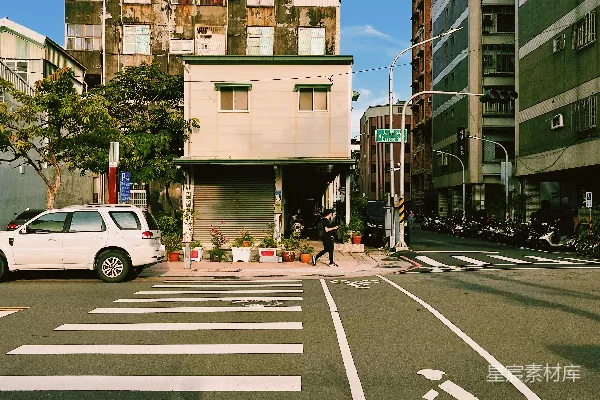 高清摄影 一辆白色汽车沿着街道行驶，旁边是高楼大厦。