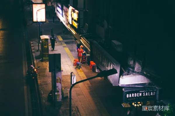 高清摄影 夜晚的城市街道，人们在人行道上行走。