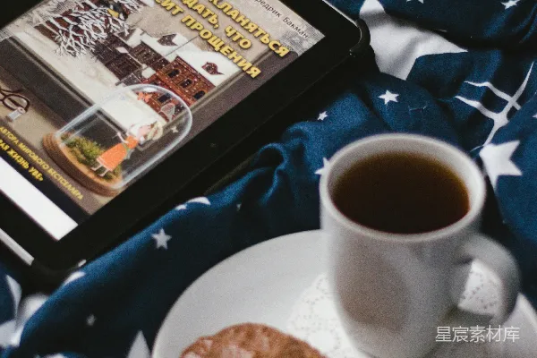 白色陶瓷茶杯置于白色陶瓷盘中，旁边放着饼干。