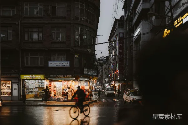 高清摄影 一个男人骑自行车沿着一排高楼旁边的一条街道行驶。